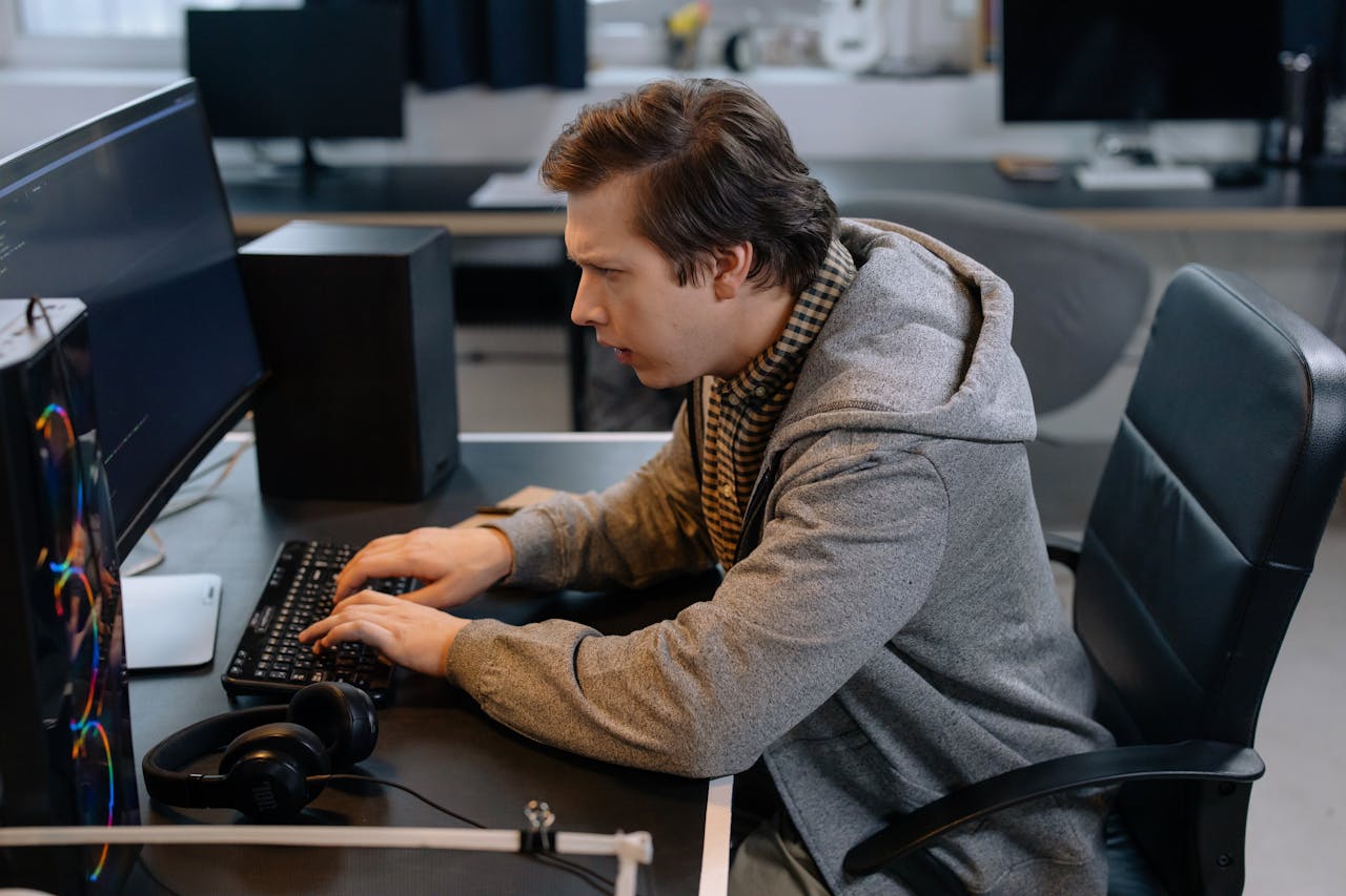 services-03 Focused male programmer working at office desk, coding efficiently.