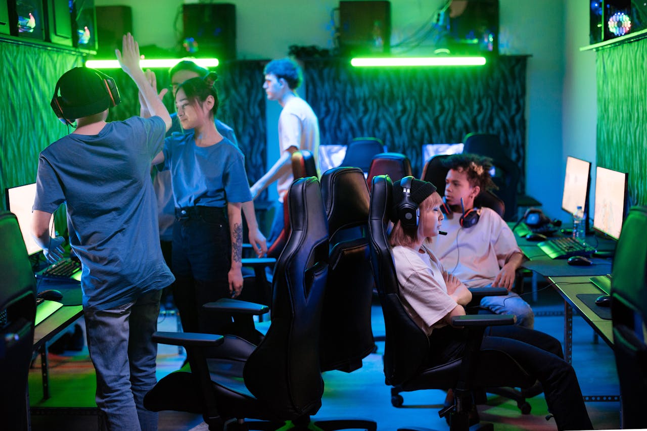 hero-img-02 A diverse group of young gamers enjoying an energetic session in a vibrant esports arena, showcasing teamwork and excitement.
